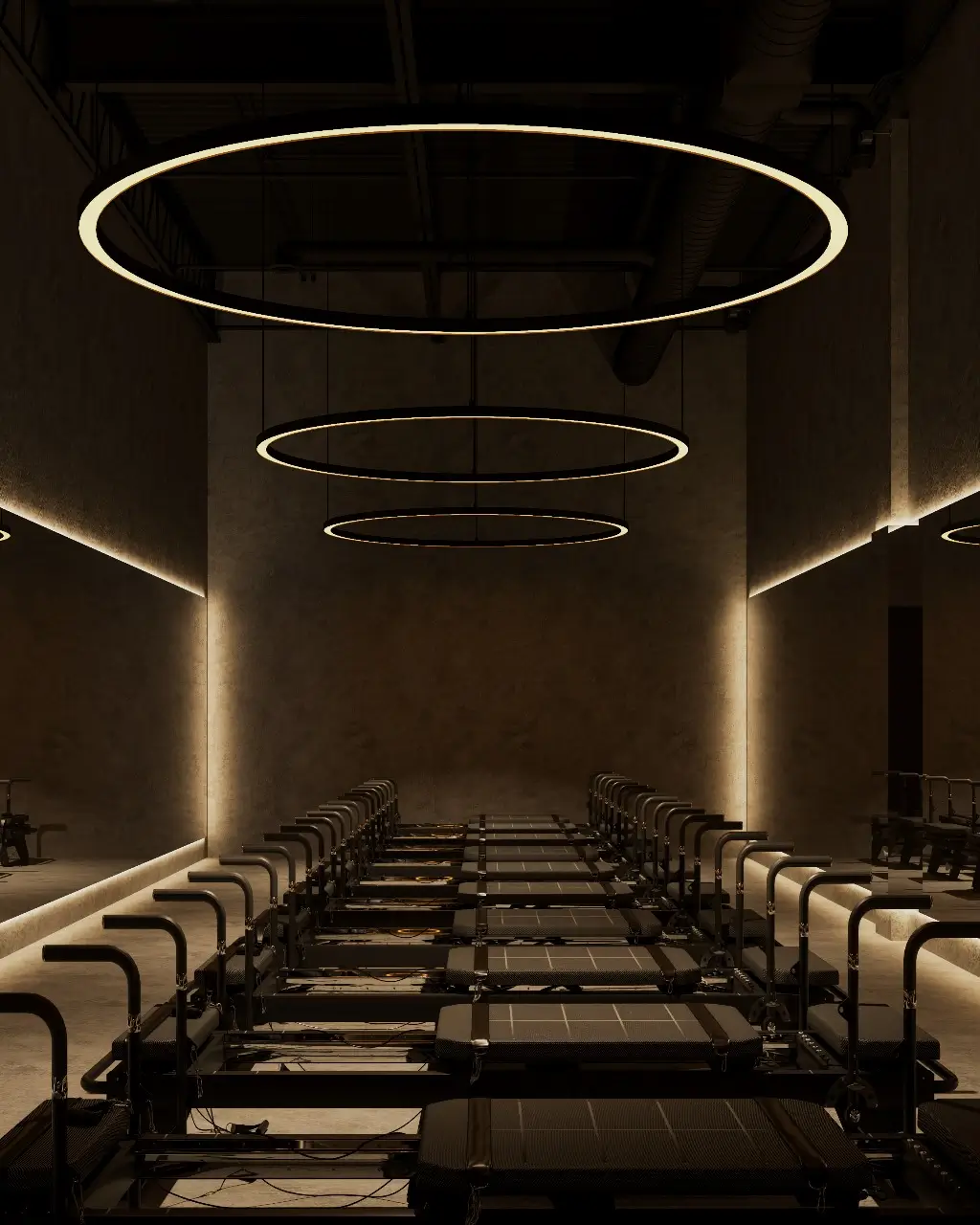 Modern Pilates studio with multiple reformer machines, ambient lighting, and circular ceiling lights